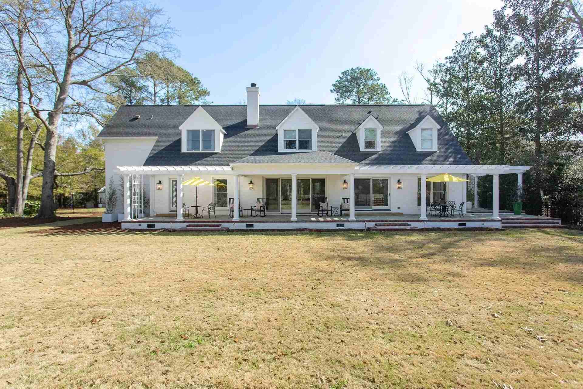 Backyard view of a custom-built home with covered porch and outdoor seating in Wilmington, NC by Balding Design Build