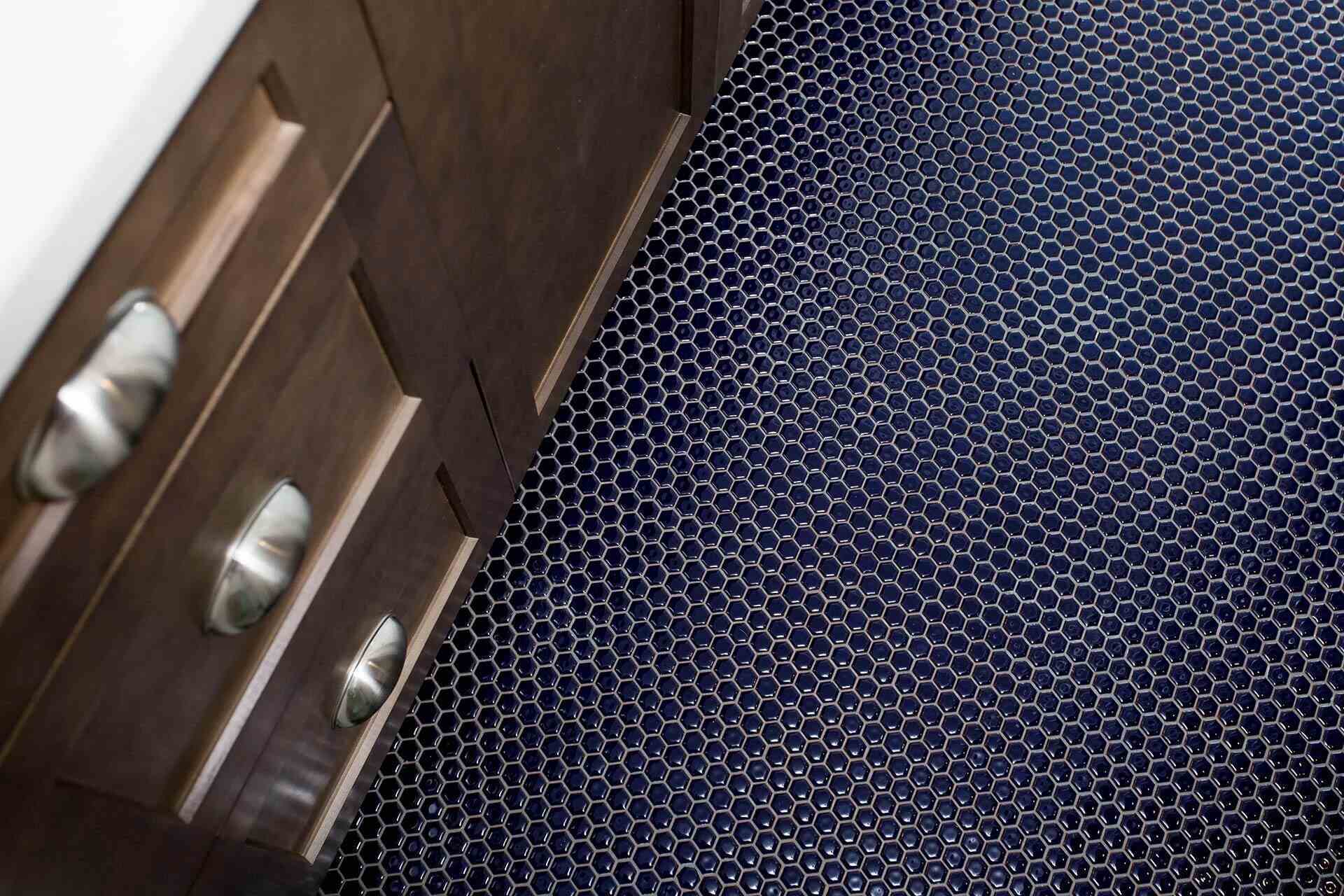 Bold navy hexagon tile flooring with wood cabinetry in a Wilmington, NC custom home bathroom by Balding Design Build
