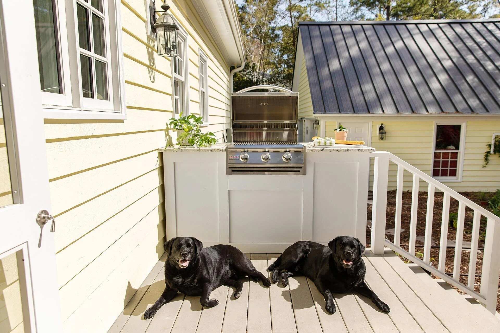 Built-in outdoor grill with two black labradors lounging on the deck of a Wilmington, NC custom home by Balding Design Build