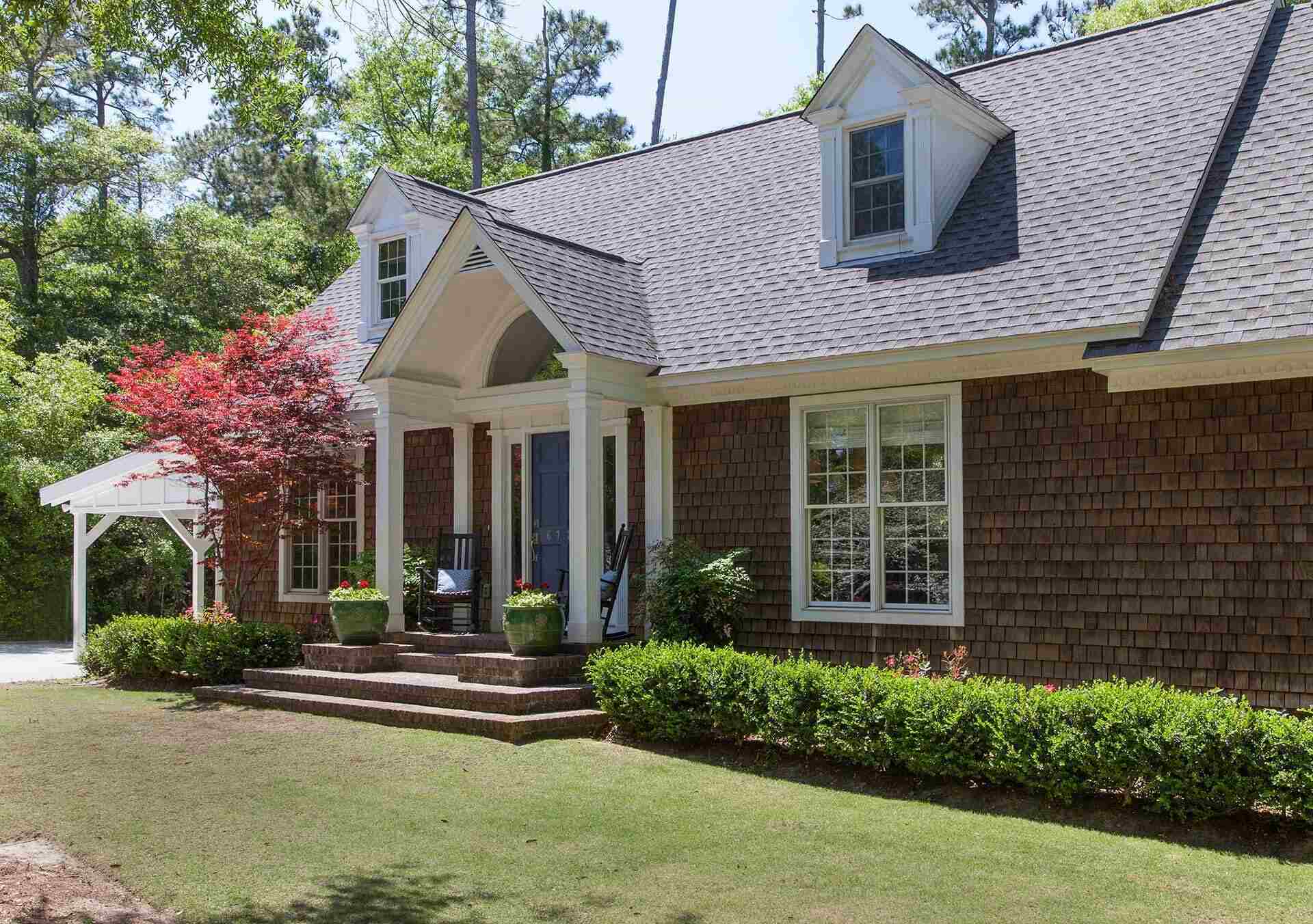 Cedar-shake exterior custom home with columned porch and manicured landscaping by Balding Design Build in Wilmington, NC