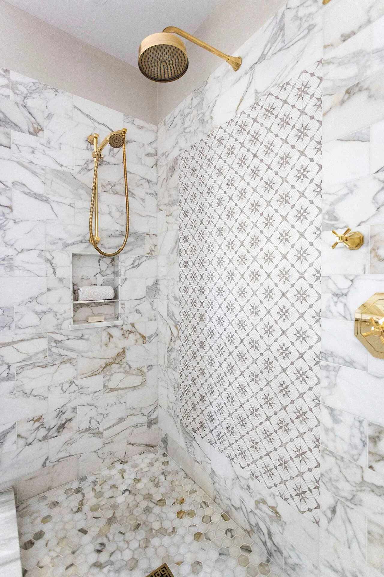 Close-up of luxurious marble shower with gold rainhead fixture in a Balding Design Build custom home in Wrightsville Beach, NC