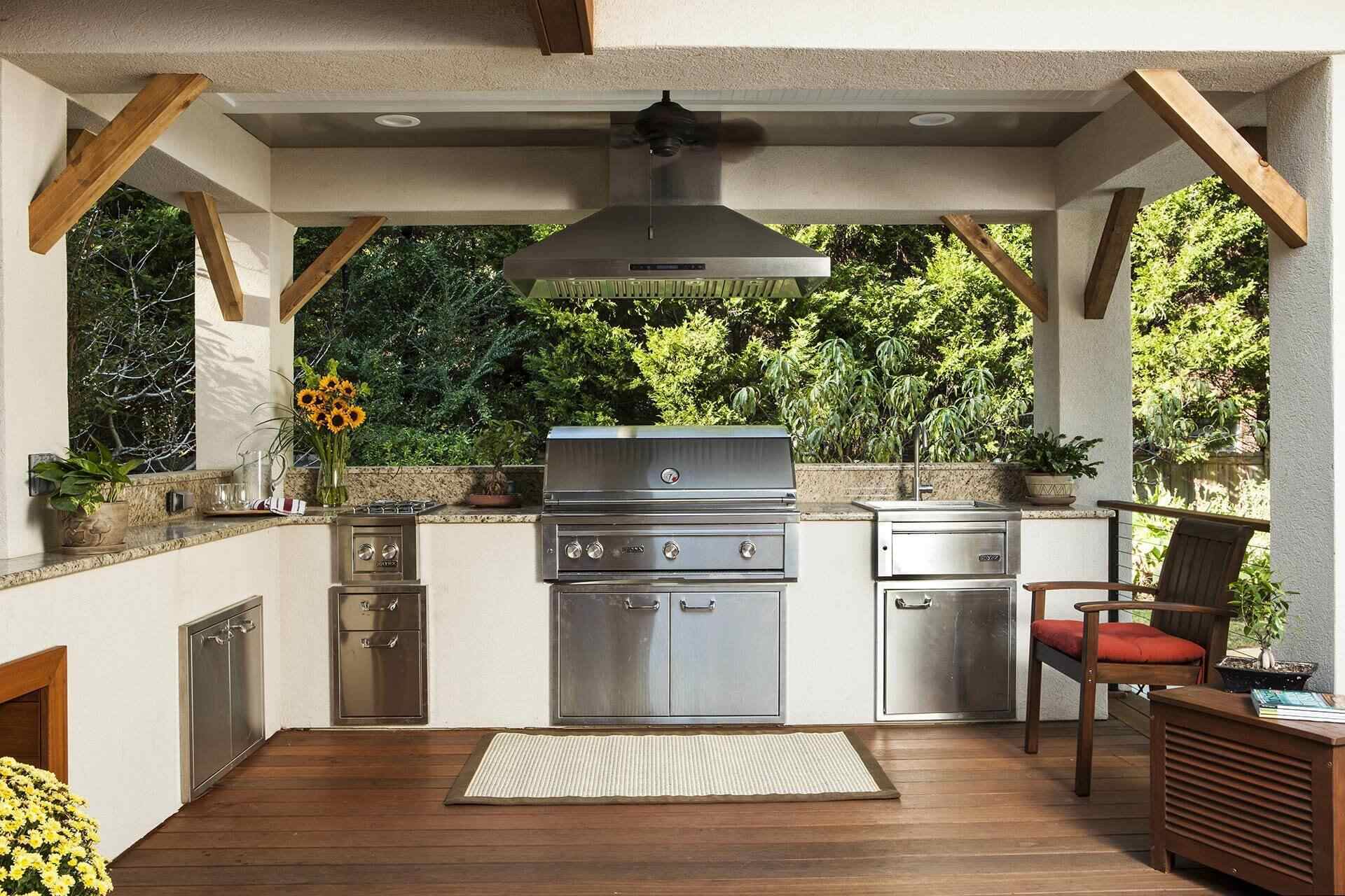 Outdoor kitchen with stainless steel appliances and wood decking by Balding Design Build in Porters Neck Plantation, NC