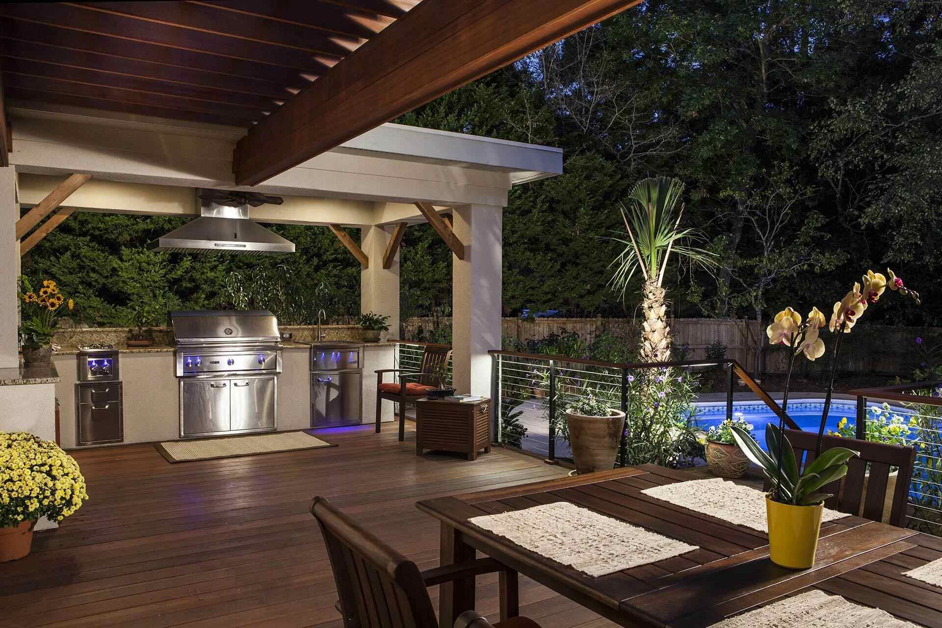Covered outdoor kitchen with stainless grill and night lighting in Wilmington, NC by Balding Design Build
