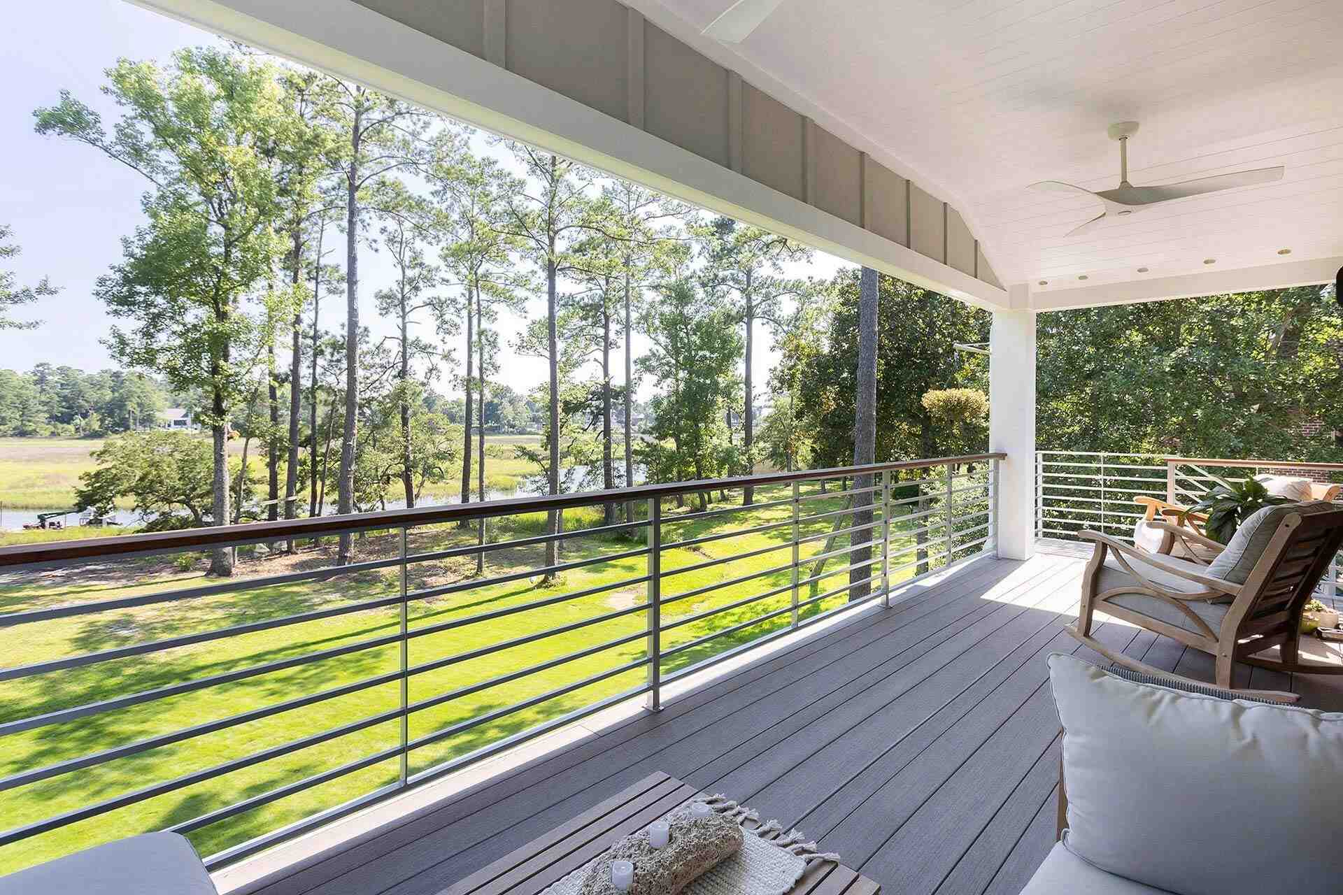 Custom home porch with cozy sectional and natural surroundings by Balding Design Build in Wilmington, NC