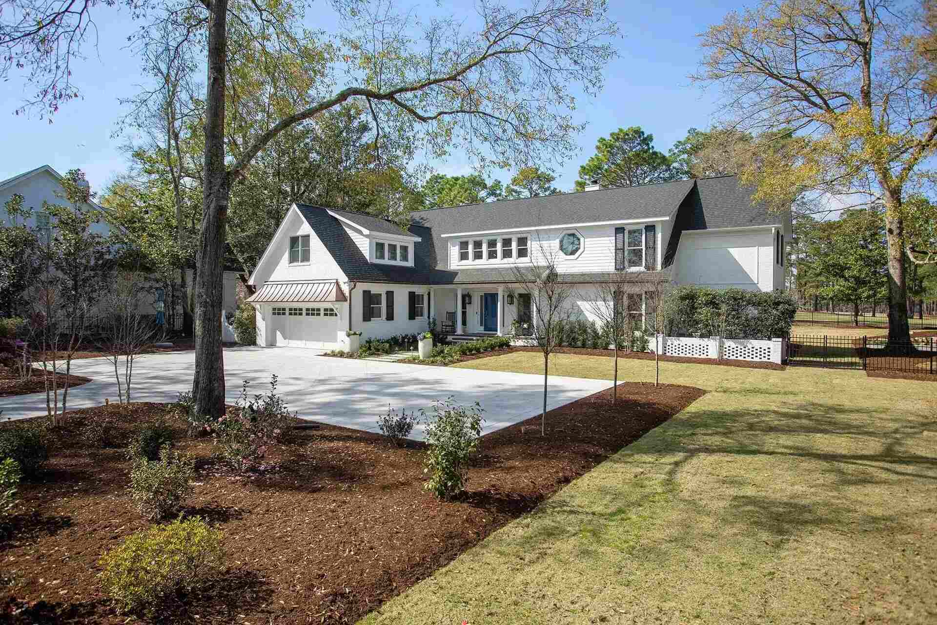 Exterior view of a luxury custom home with white brick siding and professional landscaping in Wilmington, NC by Balding Design Build