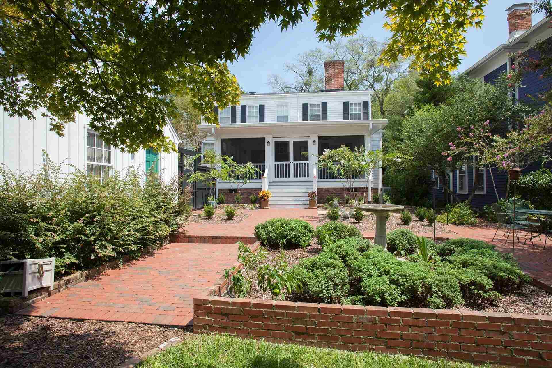 Rear view of a white historic-style custom home with screened porch and brick path by Balding Design Build in Wilmington, NC