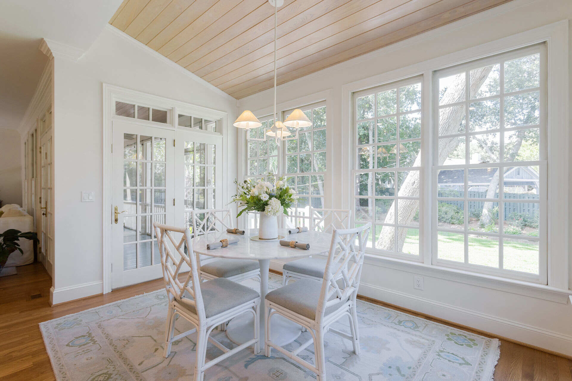 Sunlit dining area with natural wood ceiling and white furniture in a Balding Design Build custom home in Wrightsville Beach, NC