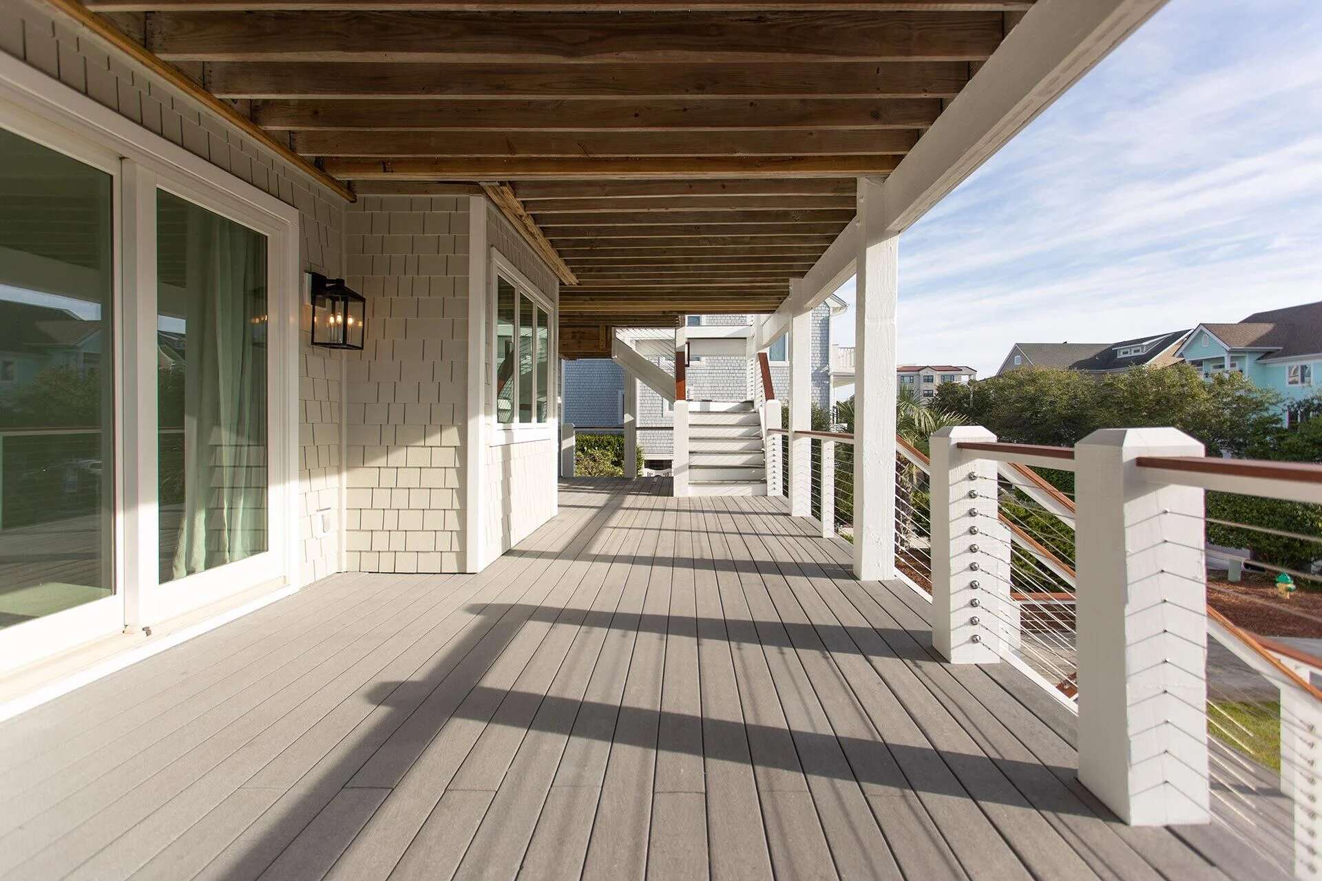 Spacious outdoor deck with exposed beams and white trim by Balding Design Build in Masonboro Loop Area, NC